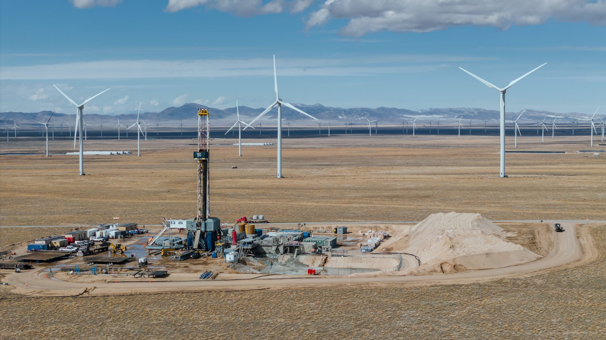 Geothermal drilling site with wind turbines